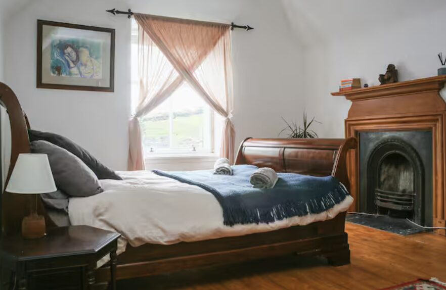 Victorian bedroom at The Old School House — original fireplace, sleigh bed and glen view
